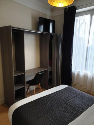 a bedroom with a bed and a chair next to a window at Hotel Le Splendid in Troyes