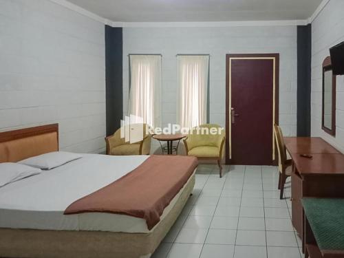 um quarto com uma cama, uma mesa e cadeiras em Kampung Resort Pertiwi RedPartner em Tagalbato