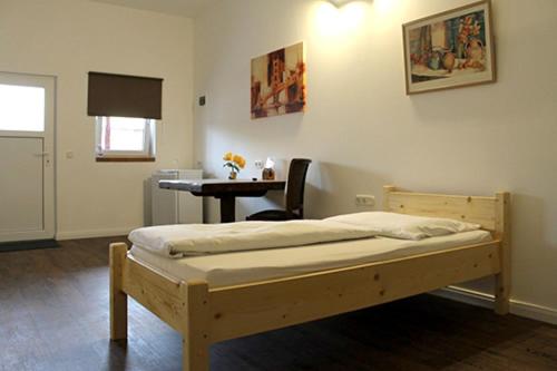 a bedroom with a wooden bed and a desk at Hotel Maximo in Pinneberg