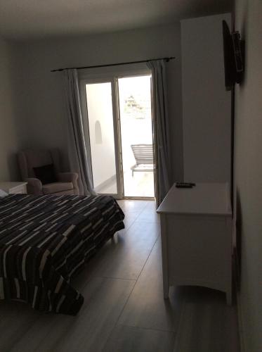 a bedroom with a bed and a door to a patio at Sailinn Mykonos in Ornos