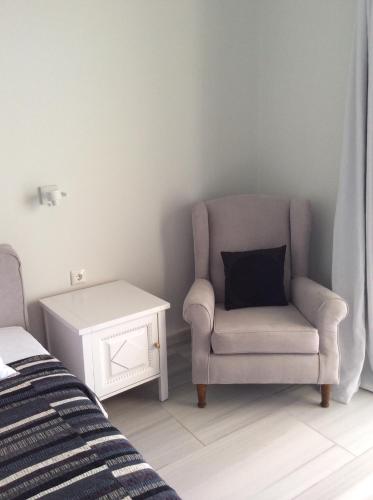 a bedroom with a chair and a side table at Sailinn Mykonos in Ornos