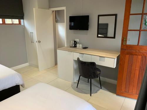 a bedroom with a desk and a chair in a room at Green Pastures Guesthouse in George