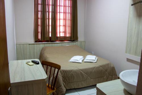 a small bedroom with a bed and a sink at Hotel Villa Souza Ltda in Santa Cruz do Sul