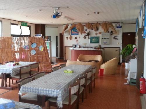 a restaurant with tables and chairs and a counter at Minshuku Myojoso in Yoron