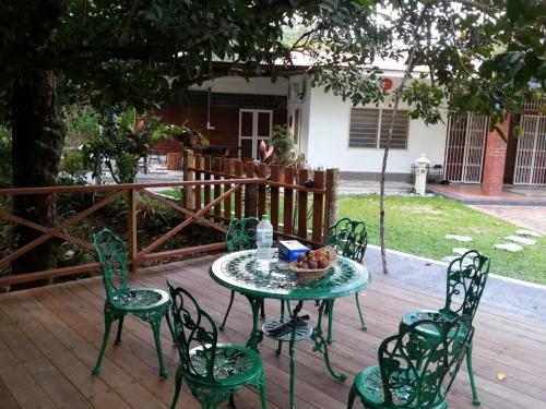 een tafel en stoelen op een houten terras bij Green Season Cottage in Sungai Lembing
