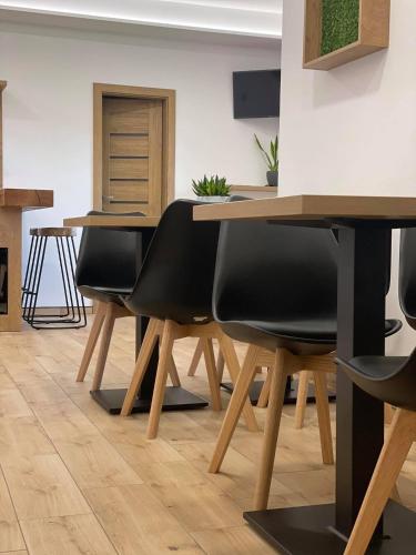 a dining room with wooden tables and black chairs at Penzion Pod Kaštanem in Nedakonitz