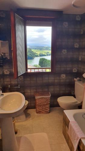 a bathroom with a sink and a toilet and a window at Tercero Loft Susana in San Vicente de la Barquera
