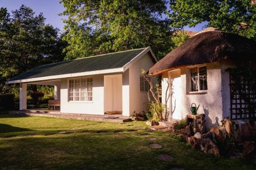 a small white house with a thatch roof at Esigodini Cottage in Underberg