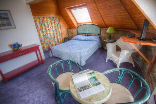 une chambre avec un lit, une table et des chaises dans l'établissement Les Rochers, à Carnac
