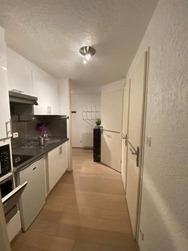  La cuisine est équipée de placards blancs et d'un réfrigérateur. dans l'établissement Location appartement saint lary 2/4 personnes, à Saint-Lary-Soulan