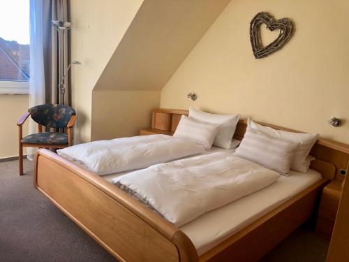 a bed with white sheets and a heart on the wall at Pension Maren in Büsum