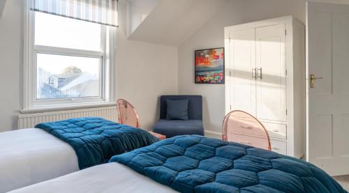 a bedroom with two beds and a blue chair at Tranquil Beachfront Beautiful 2-Bed Apartment in Deal