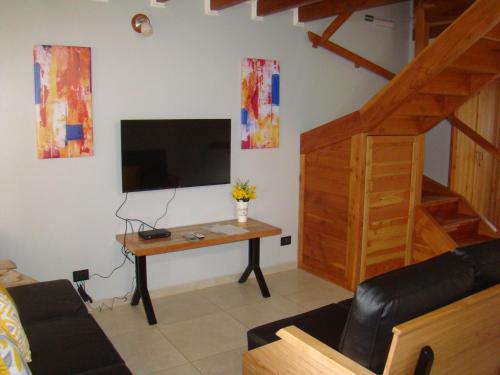 a living room with a tv and a table with a desk at Apart LAR DEL PEHUEN in Villa Pehuenia