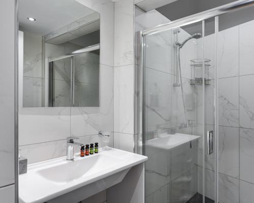 a white bathroom with a sink and a shower at Syntagma Spotlight Residence in Athens
