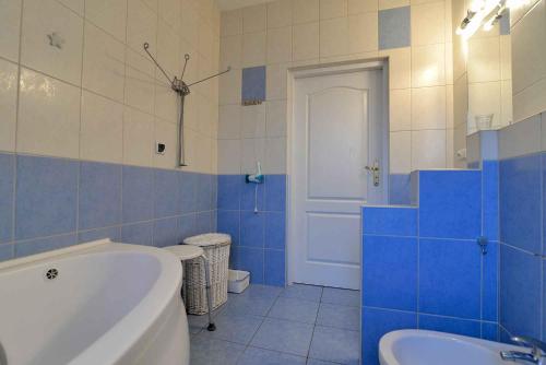 a blue and white bathroom with a tub and a sink at Słoneczny Dom in Poddąbie