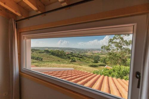une fenêtre dans une pièce avec vue sur un toit dans l'établissement Casa dos Gatos, à Lourinhã