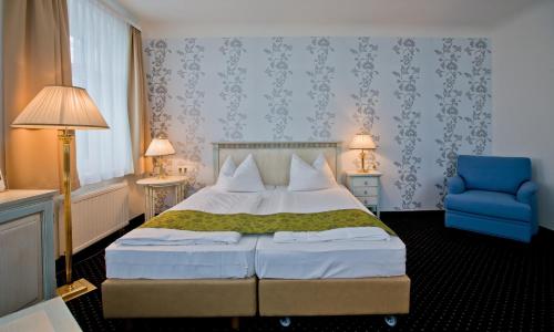 a bedroom with a bed and a blue chair at Rathaushotels All Inklusive in Kurort Oberwiesenthal