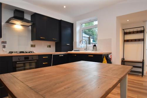 a kitchen with black cabinets and a wooden table at 4 Landgate Cottages in Winchelsea