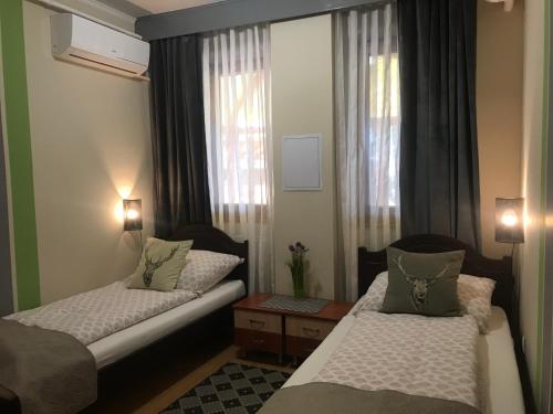 a small room with two beds and a window at Juniperus Park Hotel Kecskemét in Kecskemét