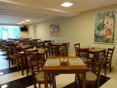 a dining room filled with wooden tables and chairs at Mar Suítes Yguassú in Nova Iguaçu