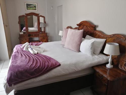 a bedroom with a large bed with purple sheets and pillows at Caledon Overnight Rooms in Kimberley