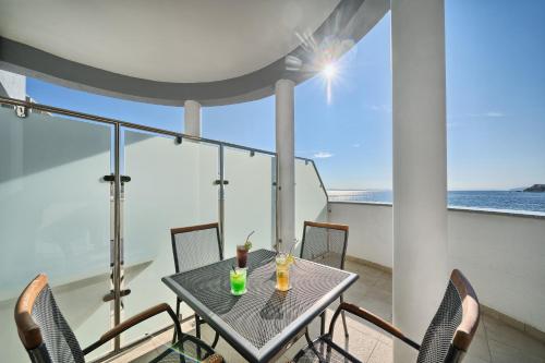 a table and chairs on a balcony with a view of the ocean at Sunset Split Rooms in Podstrana