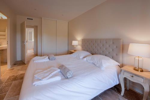 ein großes weißes Bett mit weißer Bettwäsche und Kissen in der Unterkunft Domaine de la Durantie - Villas avec Spa de nage in Castelnau-de-Montmiral
