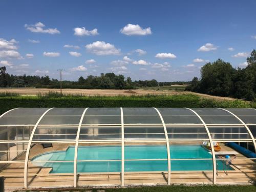 a building with a swimming pool in a field at Chambre d'hôtes des Gâtines in Berthegon