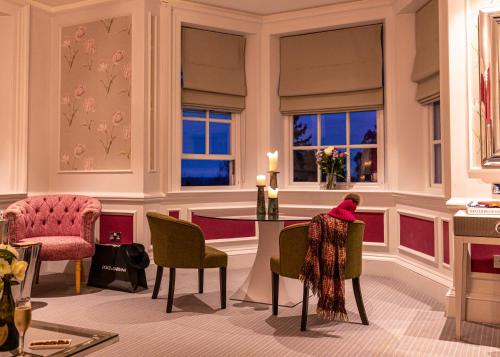 a dining room with a table and chairs and windows at Barnett Hill Hotel in Guildford