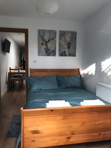 a bedroom with a wooden bed with two pictures on the wall at Modern apartment in Bexley - 25 minutes from central London in Welling