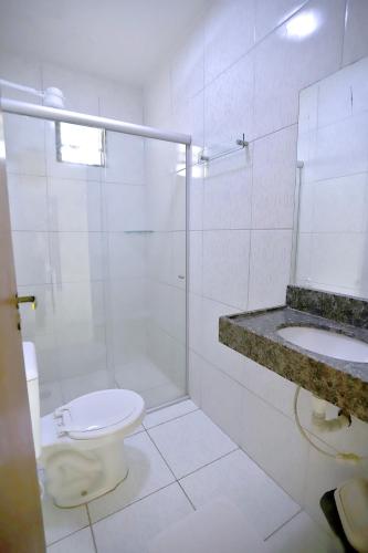 a white bathroom with a toilet and a sink at Pousada Costera in João Pessoa