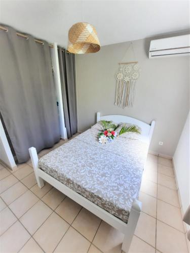 a white bed with flowers on it in a room at PLAISIRS LOCATIONS 3 ILETS in Les Trois-Îlets