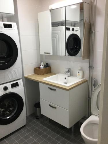 a bathroom with a sink and a washer and dryer at 2 rooms, in front of the sea, free parking in Oulu