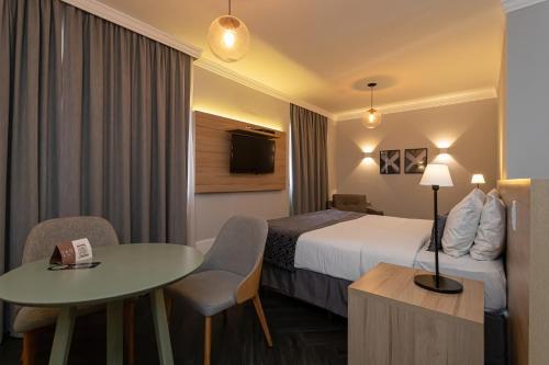 a hotel room with a bed and a table at H4 La Residence Paulista in Sao Paulo