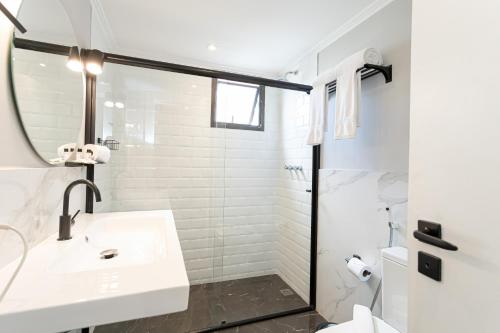 a white bathroom with a sink and a shower at H4 La Residence Paulista in Sao Paulo