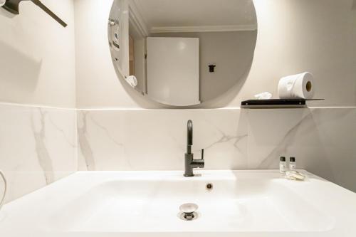 a bathroom with a white sink and a mirror at H4 La Residence Paulista in Sao Paulo