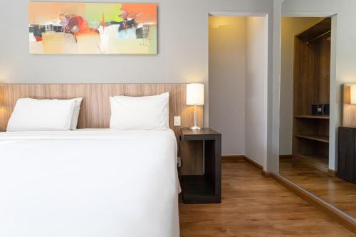 a bedroom with a bed and a table with a lamp at H4 La Residence Paulista in Sao Paulo