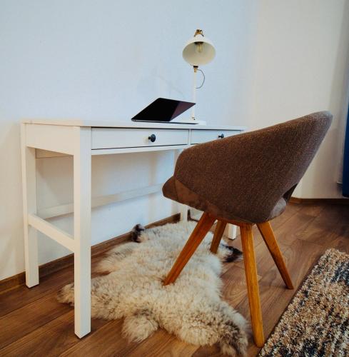a desk with a laptop and a chair on a rug at Zakarias Apartments in Miercurea-Ciuc