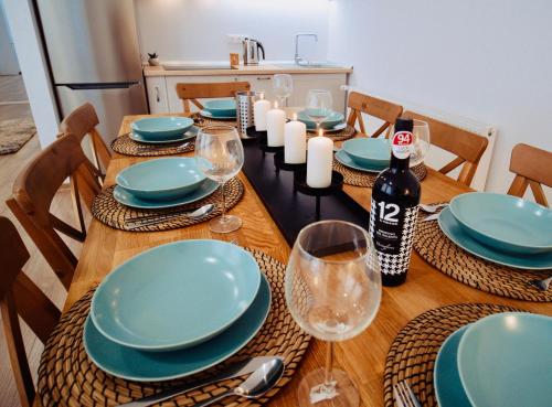 a wooden table with blue plates and wine glasses at Zakarias Apartments in Miercurea-Ciuc