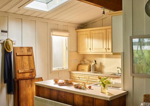 uma cozinha com armários de madeira, um lavatório e uma janela em Lochend Chalets em Port of Menteith