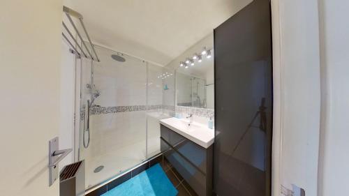 une salle de bain avec un lavabo, une douche et un miroir dans l'établissement CNN Ulysse 1 - Appartement vue mer avec garage, à La Grande Motte