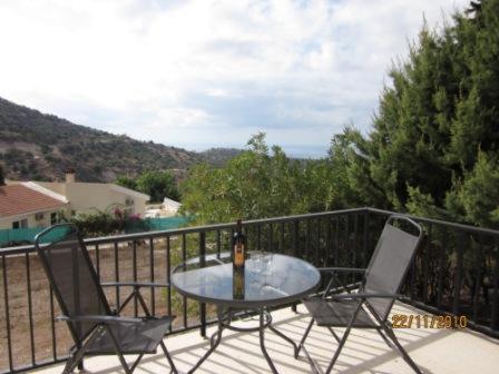 einen Tisch und Stühle auf einem Balkon mit einer Flasche Wein in der Unterkunft Bungalow with 2 double bedrooms in the hills . in Akoursos