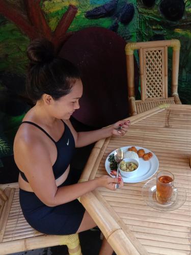 a woman sitting at a table with a plate of food at Pondok Diana Arta in Jasri