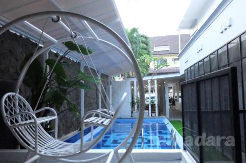 a swinging chair next to a swimming pool at Tamadara Guesthouse Jogja in Seturan