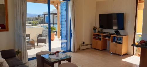 a living room with a couch and a television and a balcony at Penthouse direkt am Meer in Polis Chrysochous