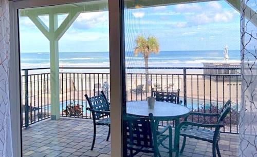 a patio with a table and chairs and the ocean at Organic Beach Retreat in Daytona Beach