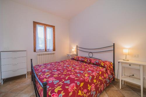 a bedroom with a bed with a red comforter at Villetta Doddy nei pressi di Barbarossa in Porto Azzurro