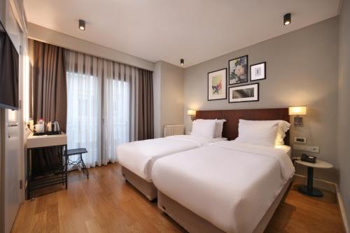 two beds in a hotel room with white sheets at Suadhan Hotel in Istanbul