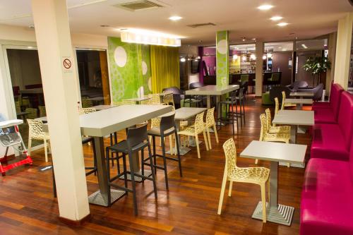 a restaurant with tables and chairs and purple chairs at ibis Styles Bethune Bruay la Buissière in Bruay-la-Buissiere