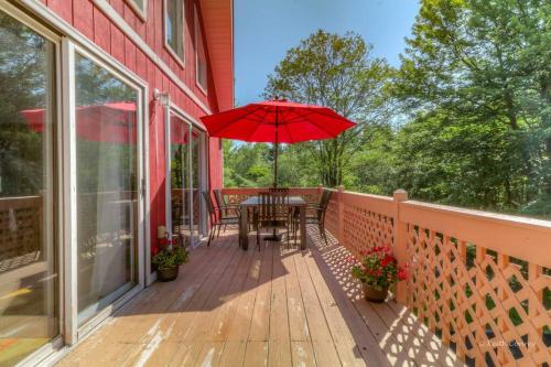 a porch with a table and a red umbrella at Beautiful Chalet with Hot Tub & Sauna in Poconos in Long Pond